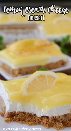 A close up of two white square small plates with a serving of a layered lemon dessert on them.