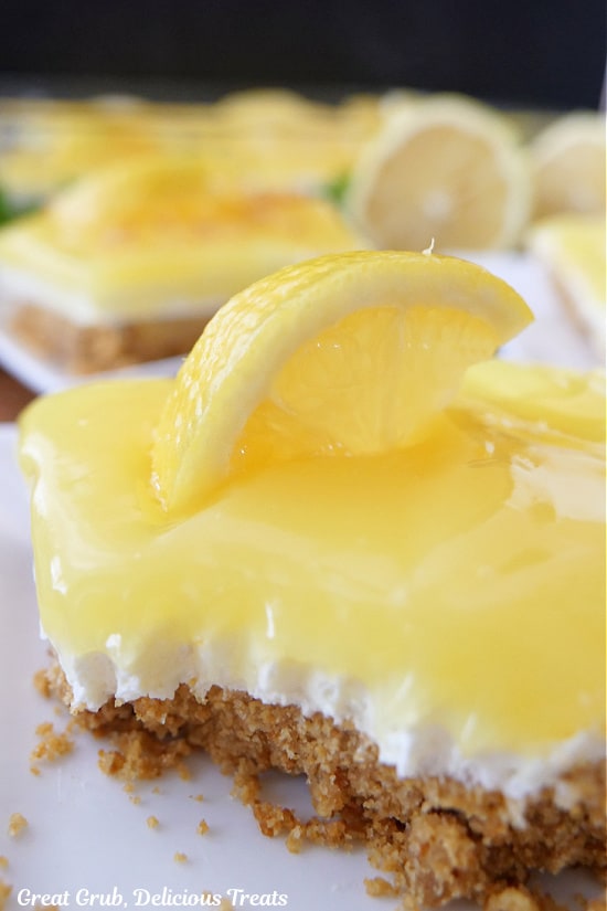 A close up of a slice of lemon cream cheese dessert with a bite taken out of it.