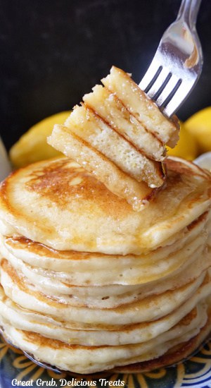 A stack of lemon ricotta pancakes with a bite of the pancakes on a fork.