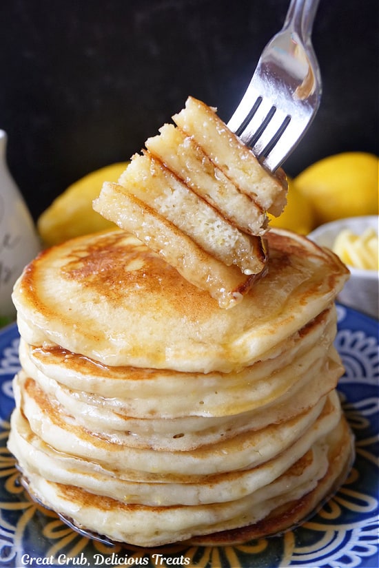 A stack of pancakes on a blue plate with a bite of pancakes on a fork.