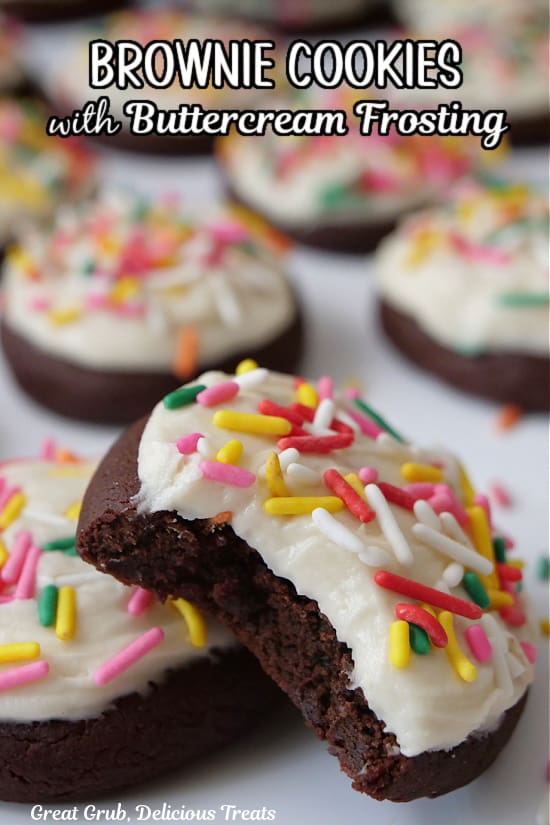 A few brownie cookies with white frosting and jimmie candy sprinkles on top with a bite out of one of the cookies.