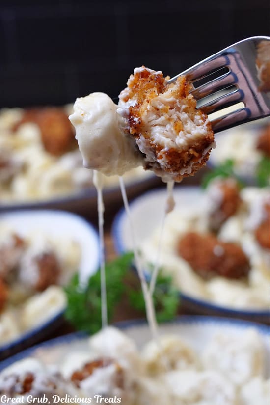 A close up of a bite of fried chicken and cheese tortellini on a fork.