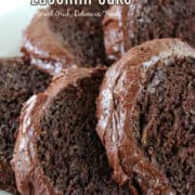 Five slices of chocolate zucchini cake with chocolate frosting on a white plate with the title at the top of the photo.