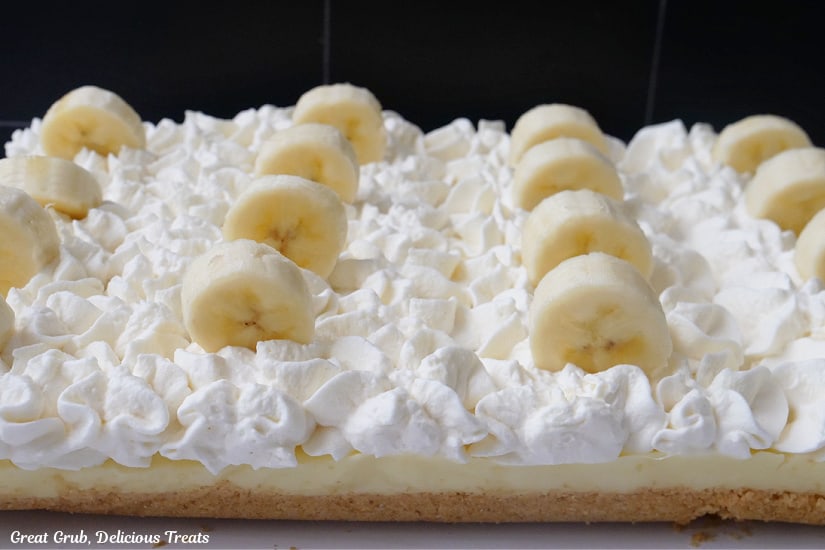 A horizontal photo of banana cream dessert before being cut into bars.