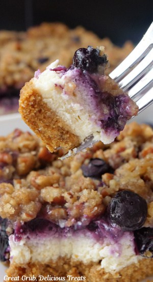 A bite of blueberry cheesecake bar on a fork showing the three different layers.