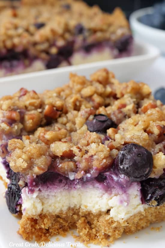 A close up of a blueberry cheesecake bar with a bite taken out of it.
