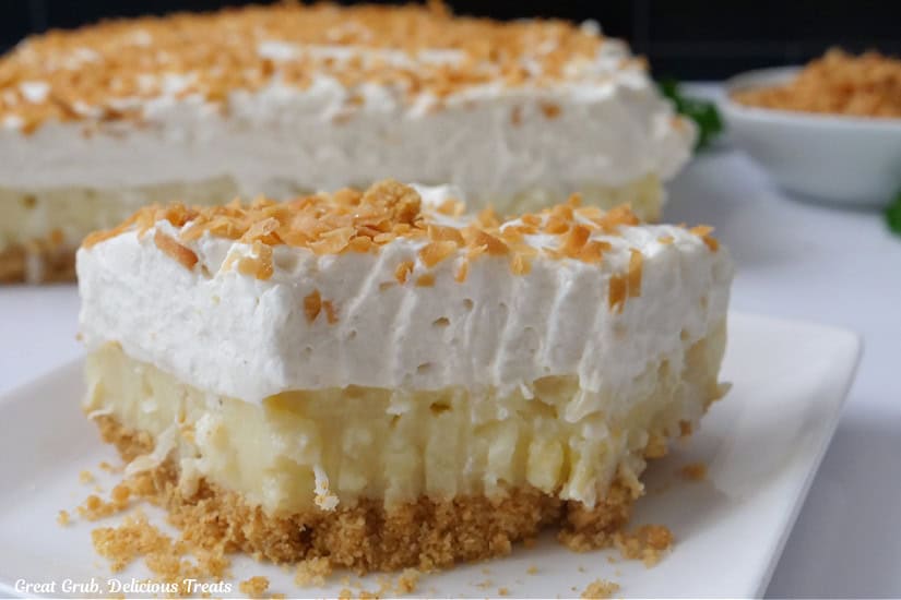 A horizontal photo of a slice of coconut cream dessert on a white plate.