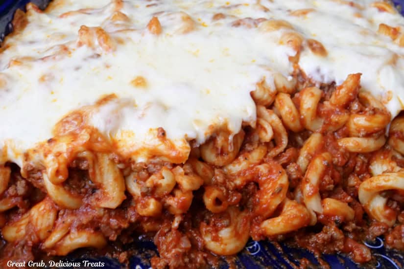 A horizontal photo of pasta with meat sauce and topped with mozzarella cheese in a casserole dish after being baked..