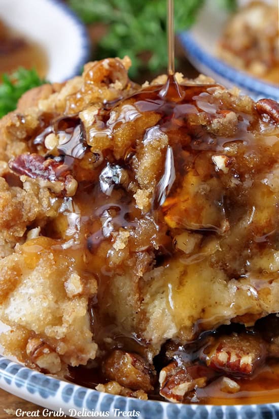 A close up of a serving of French toast bake with maple syrup being drizzled over it.