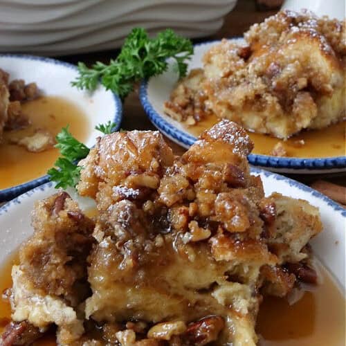 Three white round plates with blue trim with a serving of French toast bake on each plate.