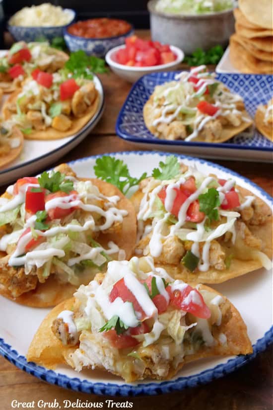 A round white plate with blue trim with three mini chicken tostadas on it.