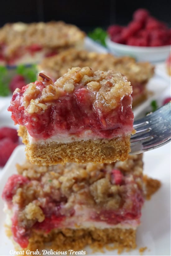 A close up of a bite of raspberry cheesecake bar on a fork.