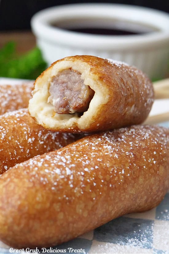 A close up of a homemade pancake sausage on a stick with a bite taken out of it.