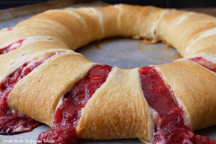 A horizontal photo of a strawberry pastry ring before it is cut into slices and right after being removed from the oven.