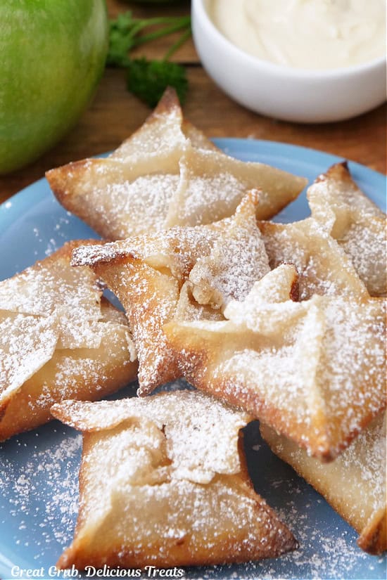 A blue plate with powdered sugar covered fried wontons.