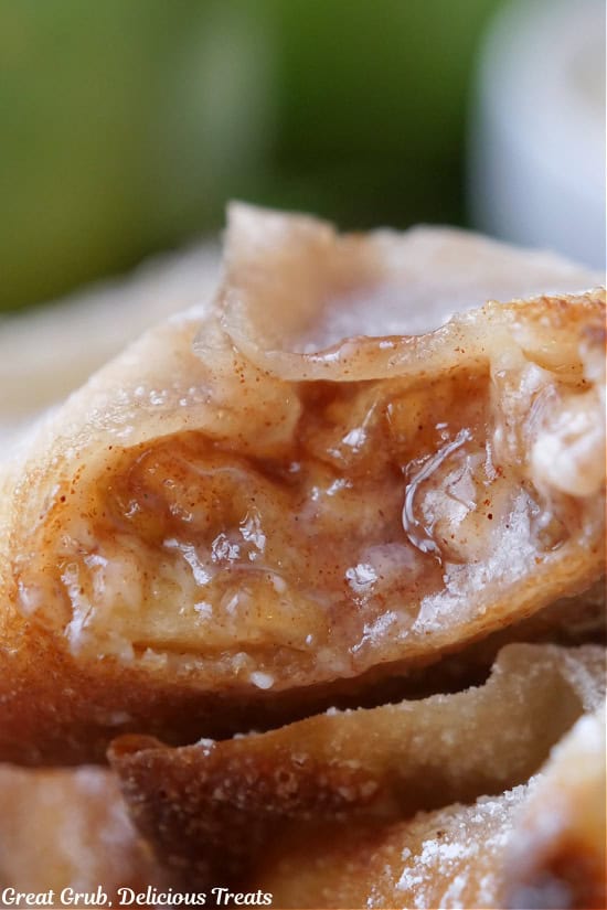 A super close up photo of a fried apple wonton with a bite taken out of it.