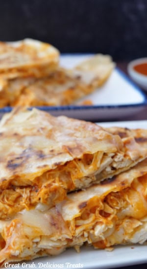 A close up of two pieces of buffalo chicken quesadillas on a white plate.