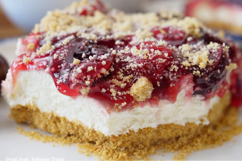 A slice of cherry cream cheese dessert placed on a white plate.
