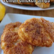 A square white plate with two chicken strips on it.