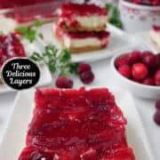 A white surface with white square plate with a serving of cranberry dessert bars on them.