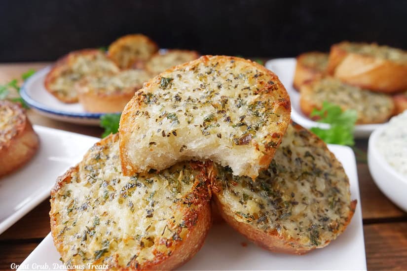 White plates with round pieces of garlic bread on them.