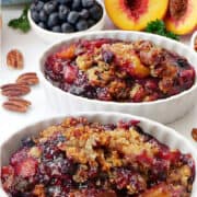 Two oval white bowls with peach blueberry cobbler in it.