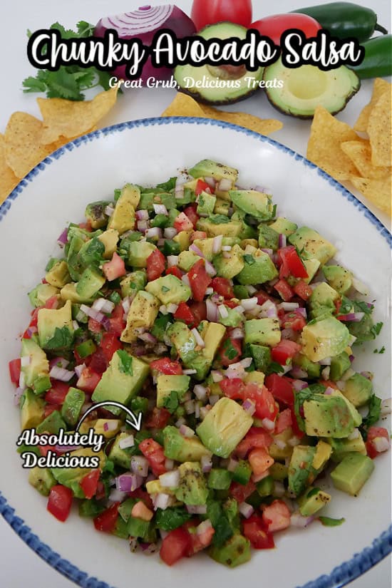 A white bowl with blue trim filled with chunky avocado salsa.