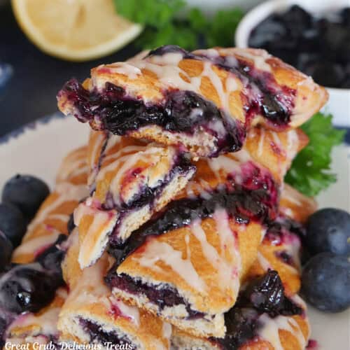 A small stack of blueberry twists on a white plate with blue trim.
