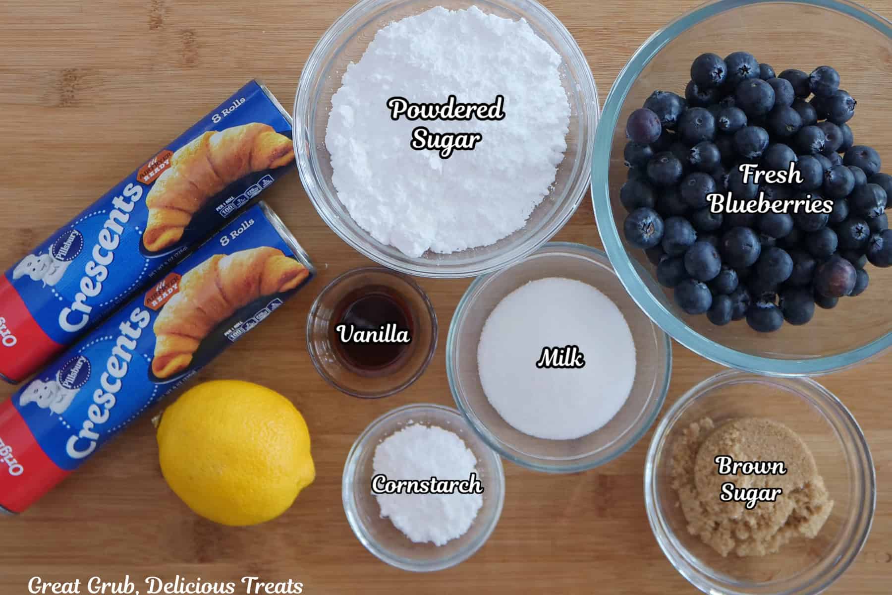 A wood surface with all the ingredients needed to make blueberry crescent cream cheese muffins.