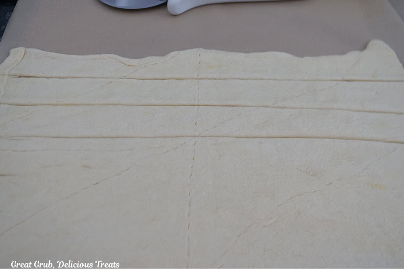 A piece of parchment paper on a counter with a crescent dough rolled out flat.