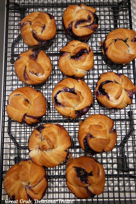 A wire rack with 12 blueberry crescent cream cheese muffins on it.