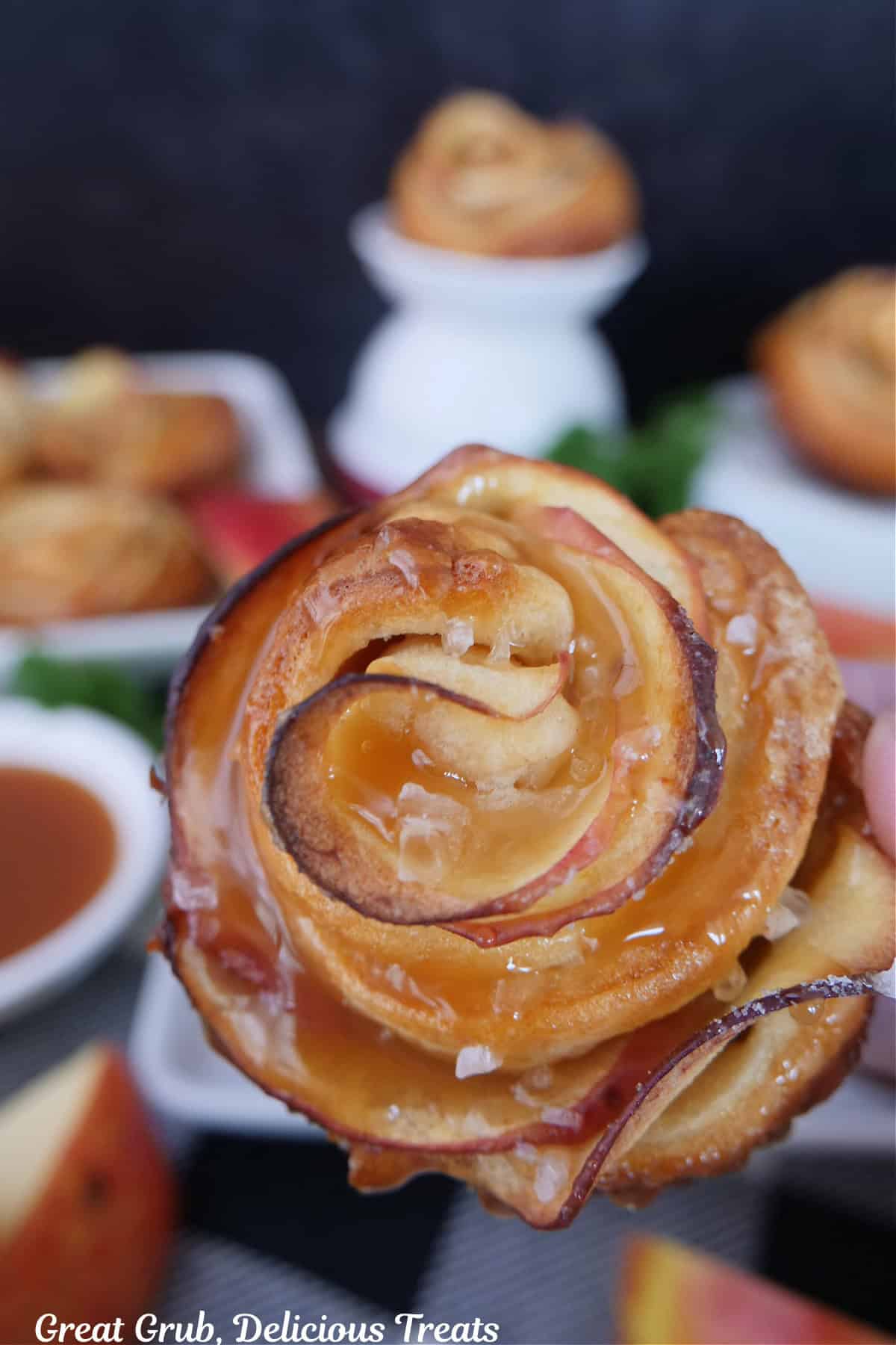 A caramel apple rose held up above more apple roses underneath it.