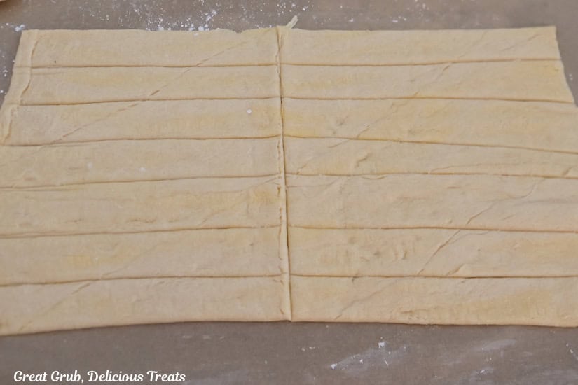 A crescent dough rolled out and cut into 7 long strips and then are cut in half making 14 strips.