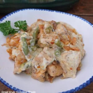 A white bowl with blue trim with cheesy chicken green bean casserole in it.