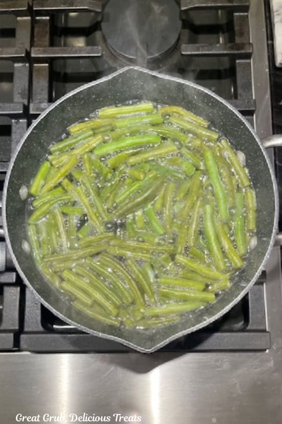 A pan on the stove filled with water par-boiling fresh green beans.