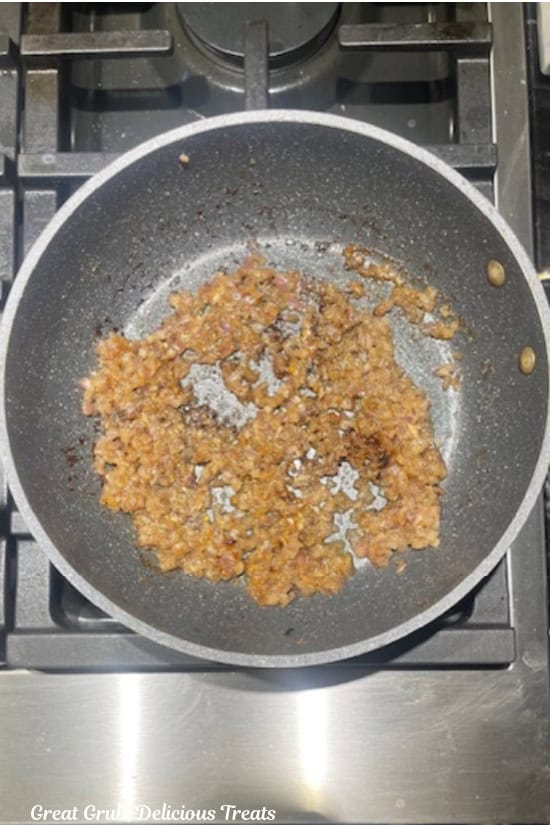 A pan with onions and garlic sautéing in it.