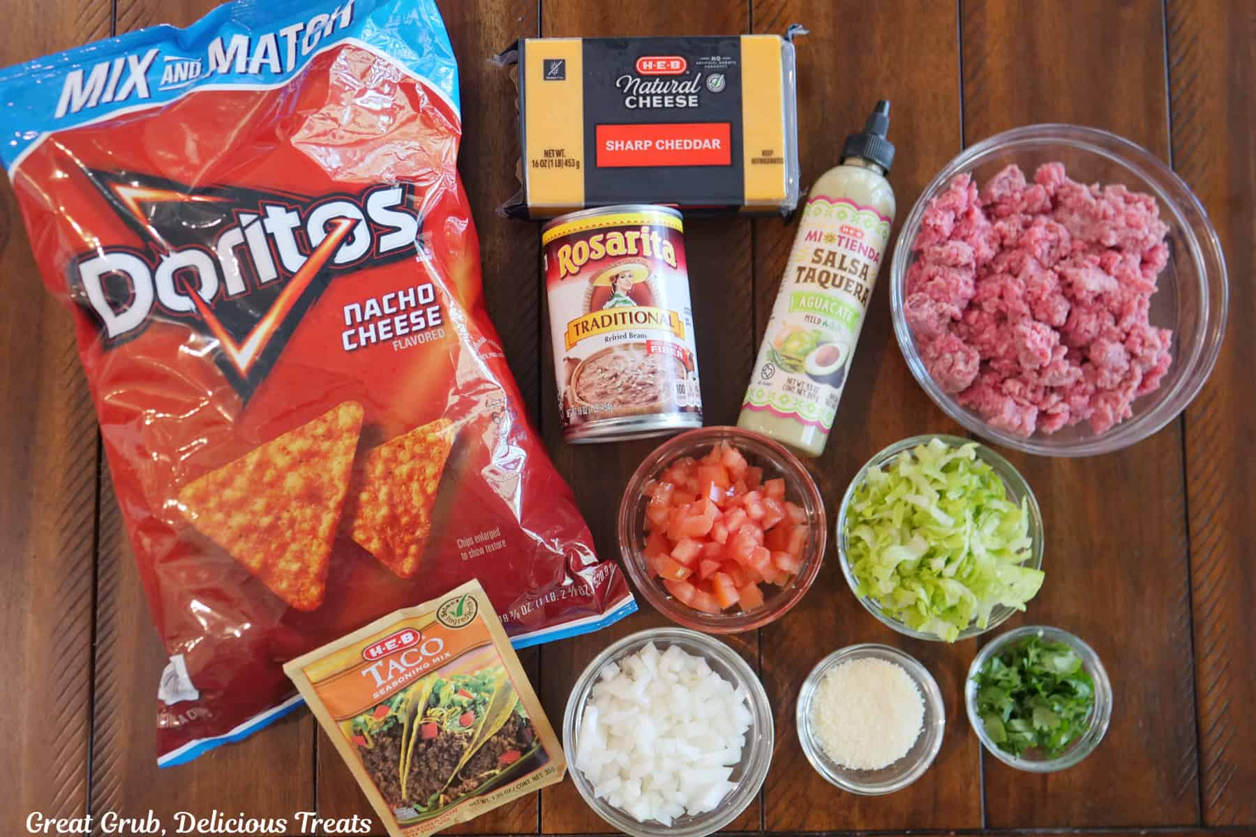 A wood surface with all the ingredients needed to make cheesy crunch mini tacos on it.