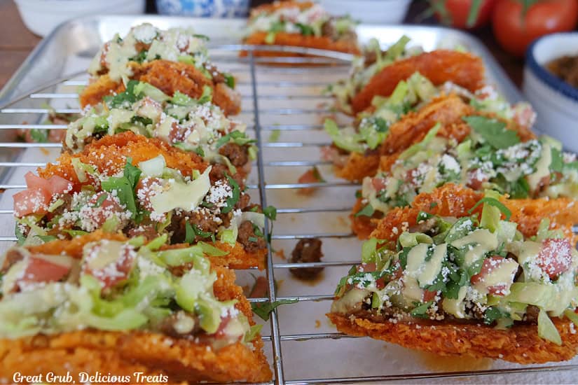 A wire rack placed over a baking sheet with cheesy crunch tacos on it.