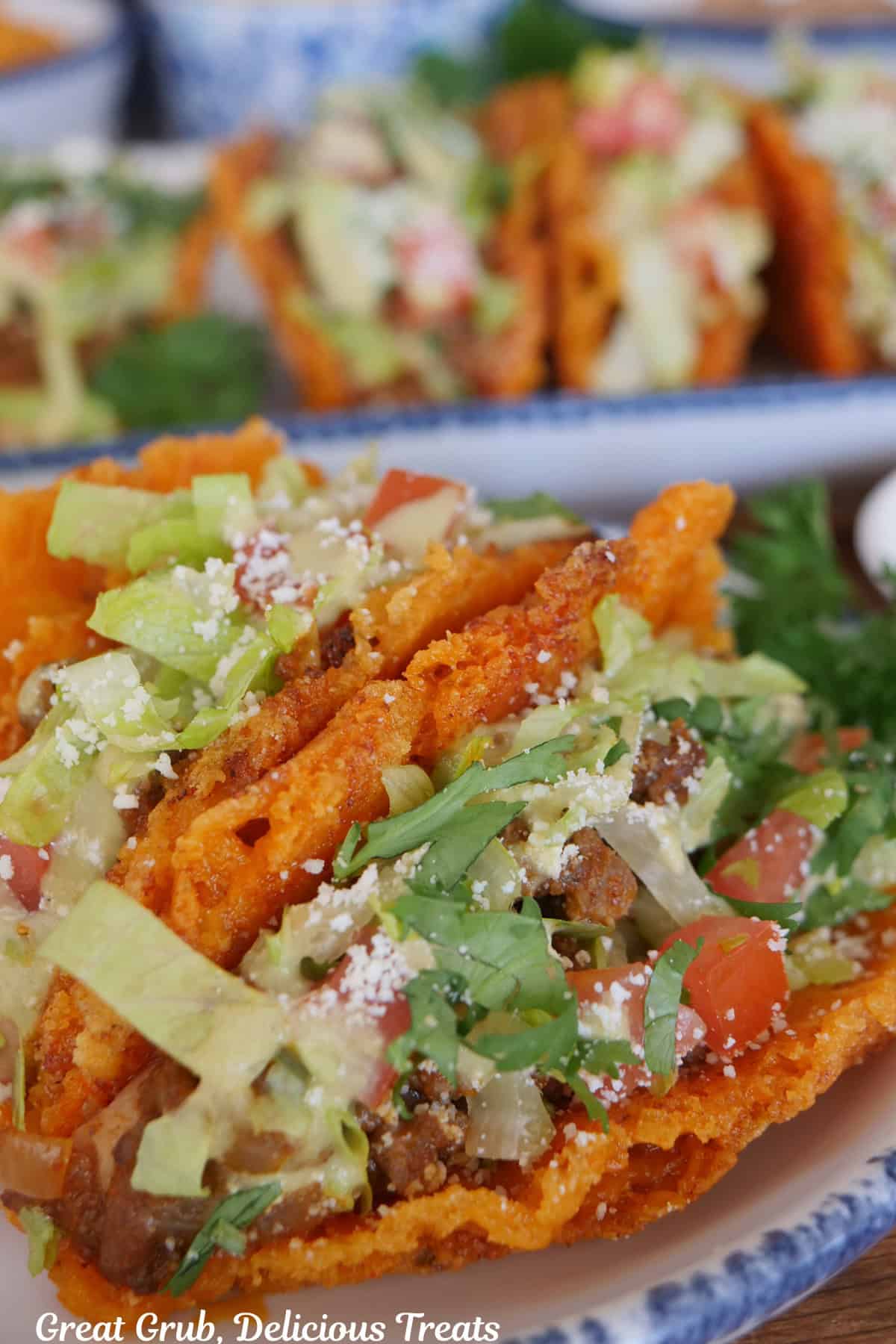 A white round plate with blue trim with three cheesy crunch mini tacos on it.