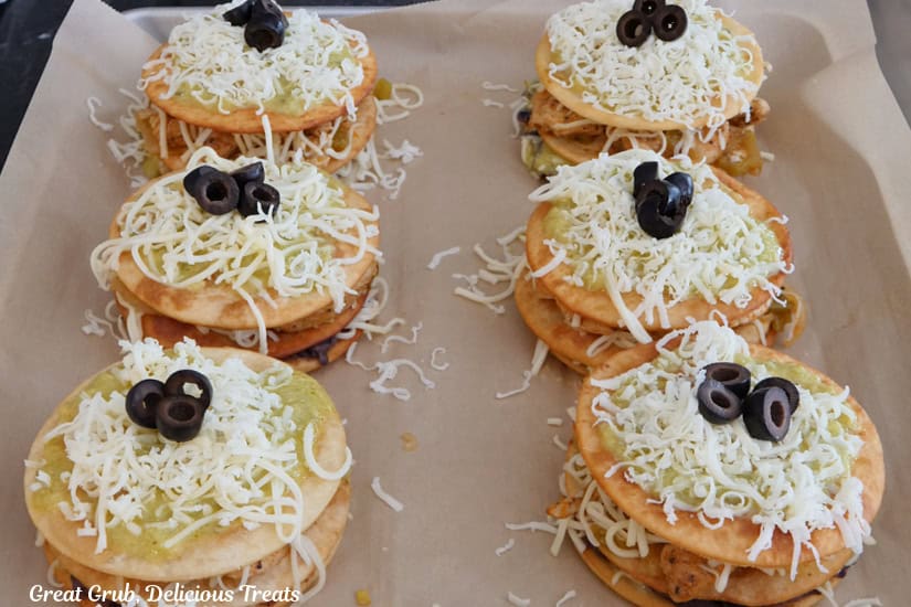 A parchment paper lined baking sheet with six mini Mexican pizzas on it before going in the oven.