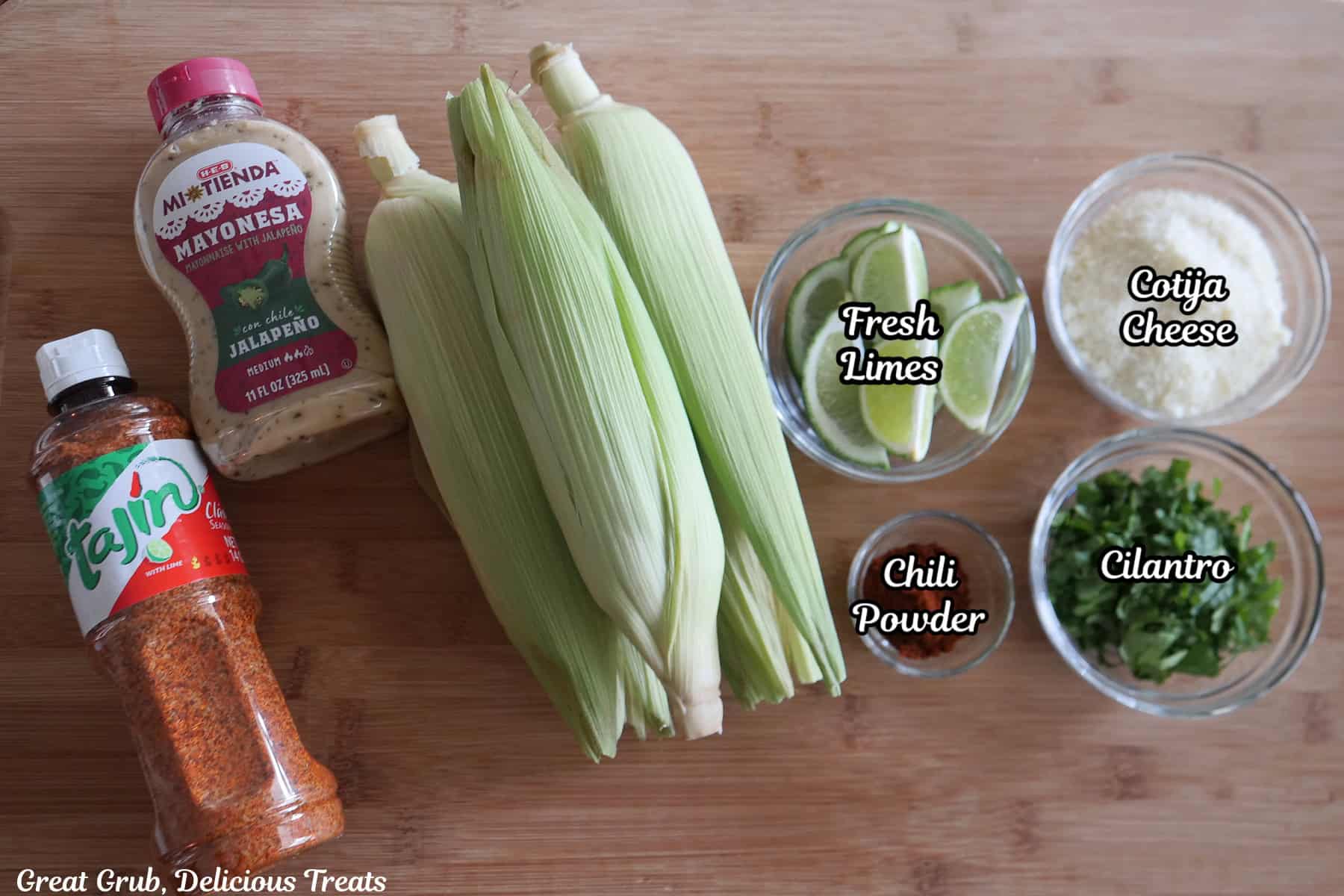 A wood surface with all the ingredients needed to make grilled jalapeno elote on it.