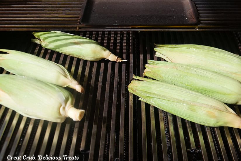 Grill grates with 6 ears of corn on it.