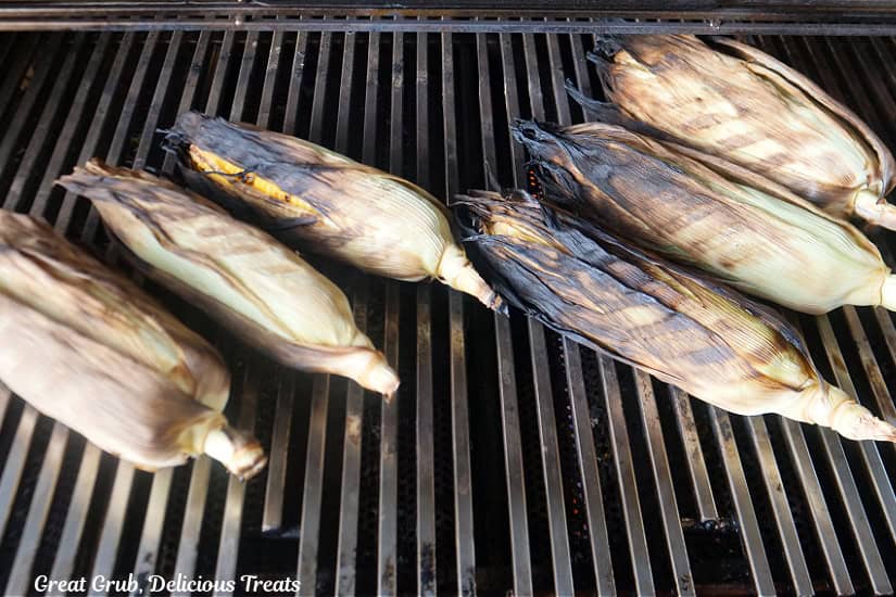 Grill grates with 6 ears of grilled corn on the cob on them.
