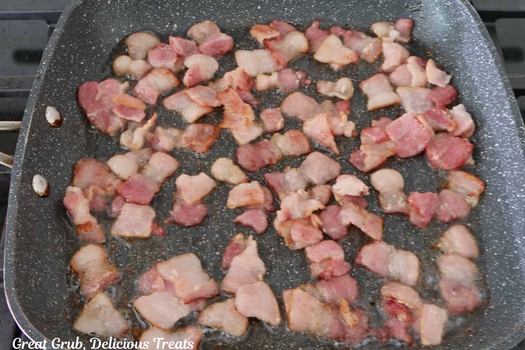 Bacon that has been cut into small pieces, frying in a pan.