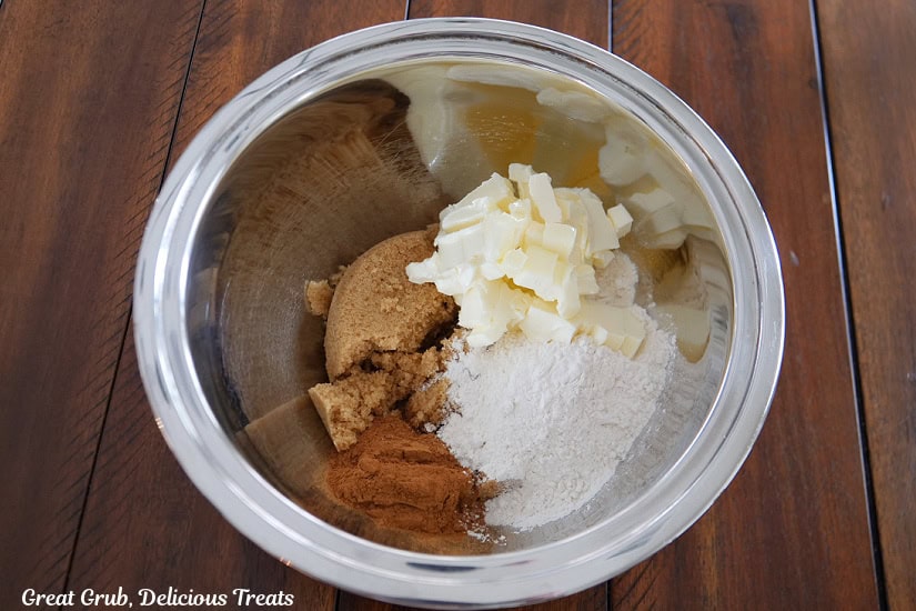 A silver mixing bowl with butter, brown sugar, flour, and cinnamon in it.