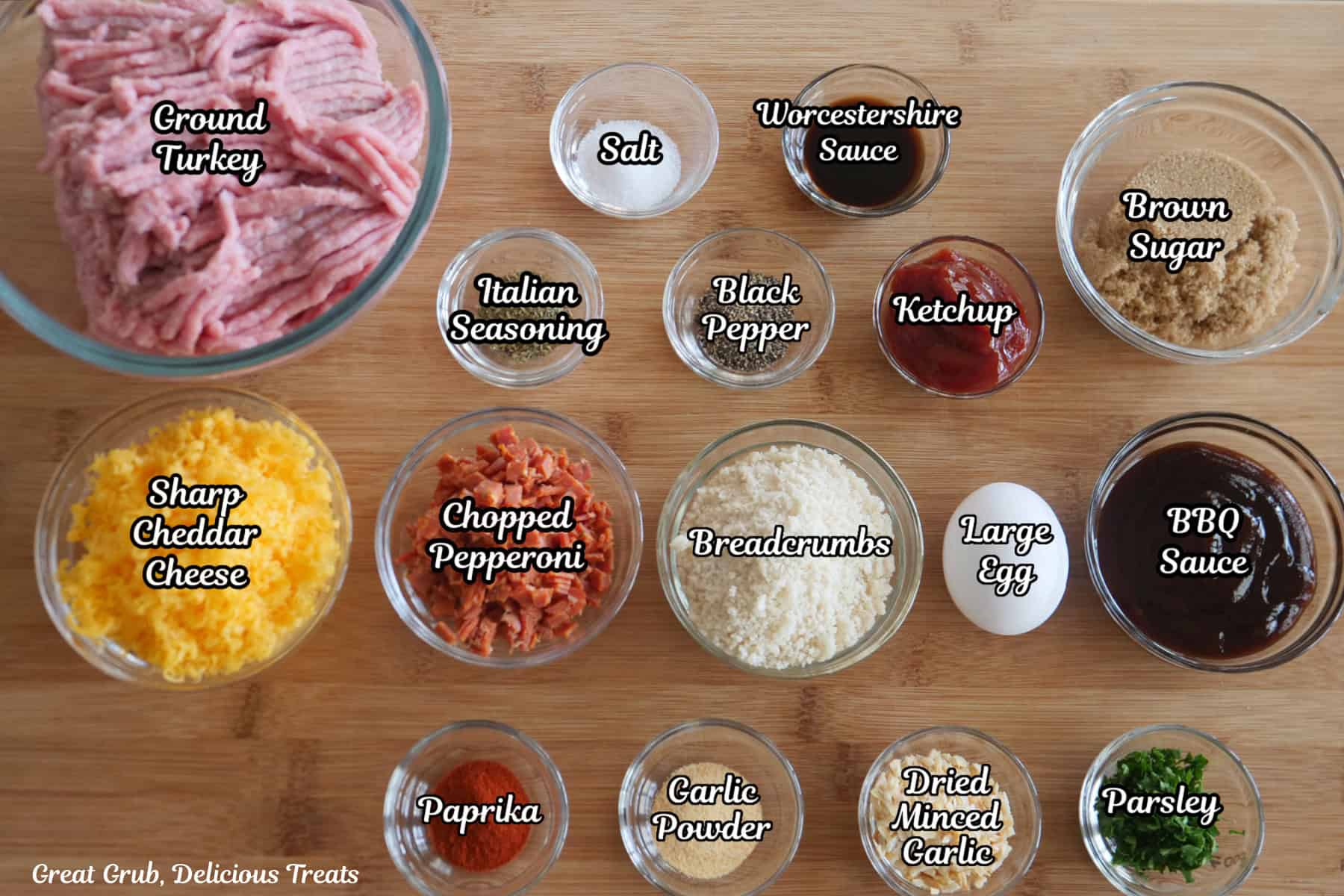 A wood surface with all the ingredients needed to make mini turkey meatloaves on it.