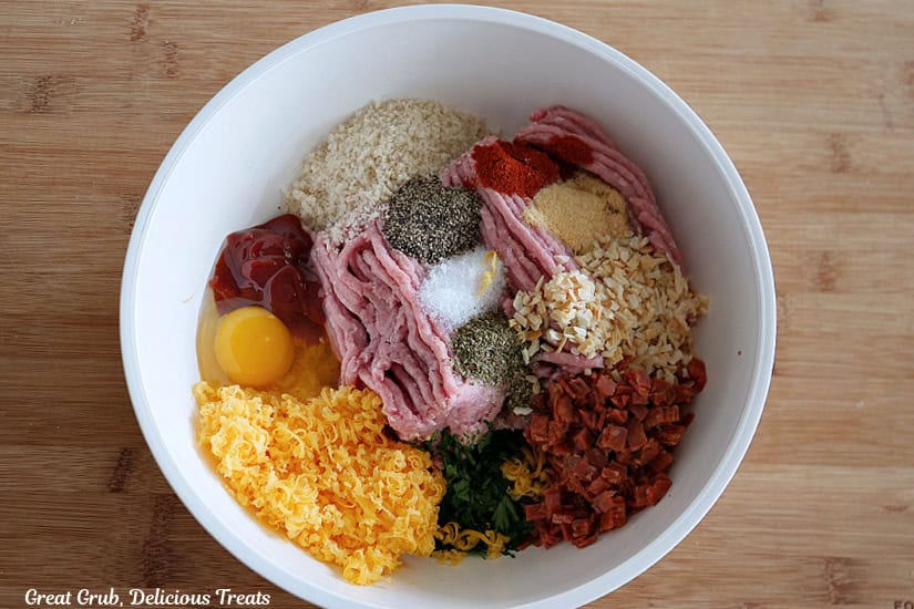 A wood surface with a light blue bowl filled with turkey meatloaf ingredients in it before being mixed together.