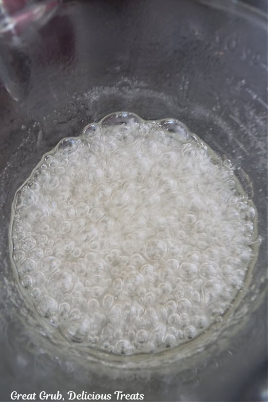 A glass microwave safe bowl with boiling sugar and corn syrup in it.