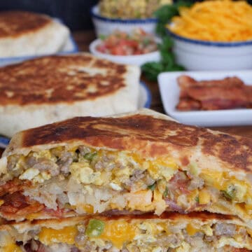 A white plate with a taco bell breakfast crunch wrap cut in half and stacked on top of each other showing all the inside ingredients.