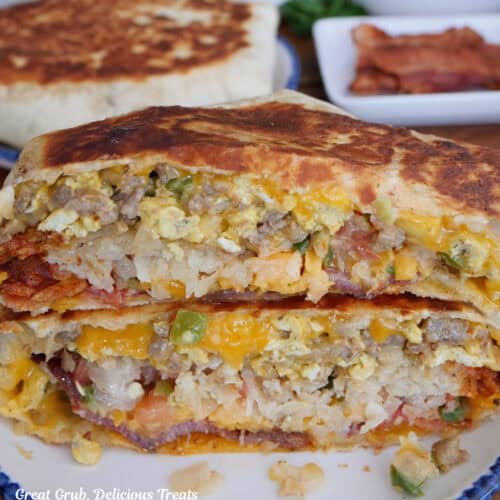 A round white plate with blue trim with a breakfast crunch wrap stacked on it.